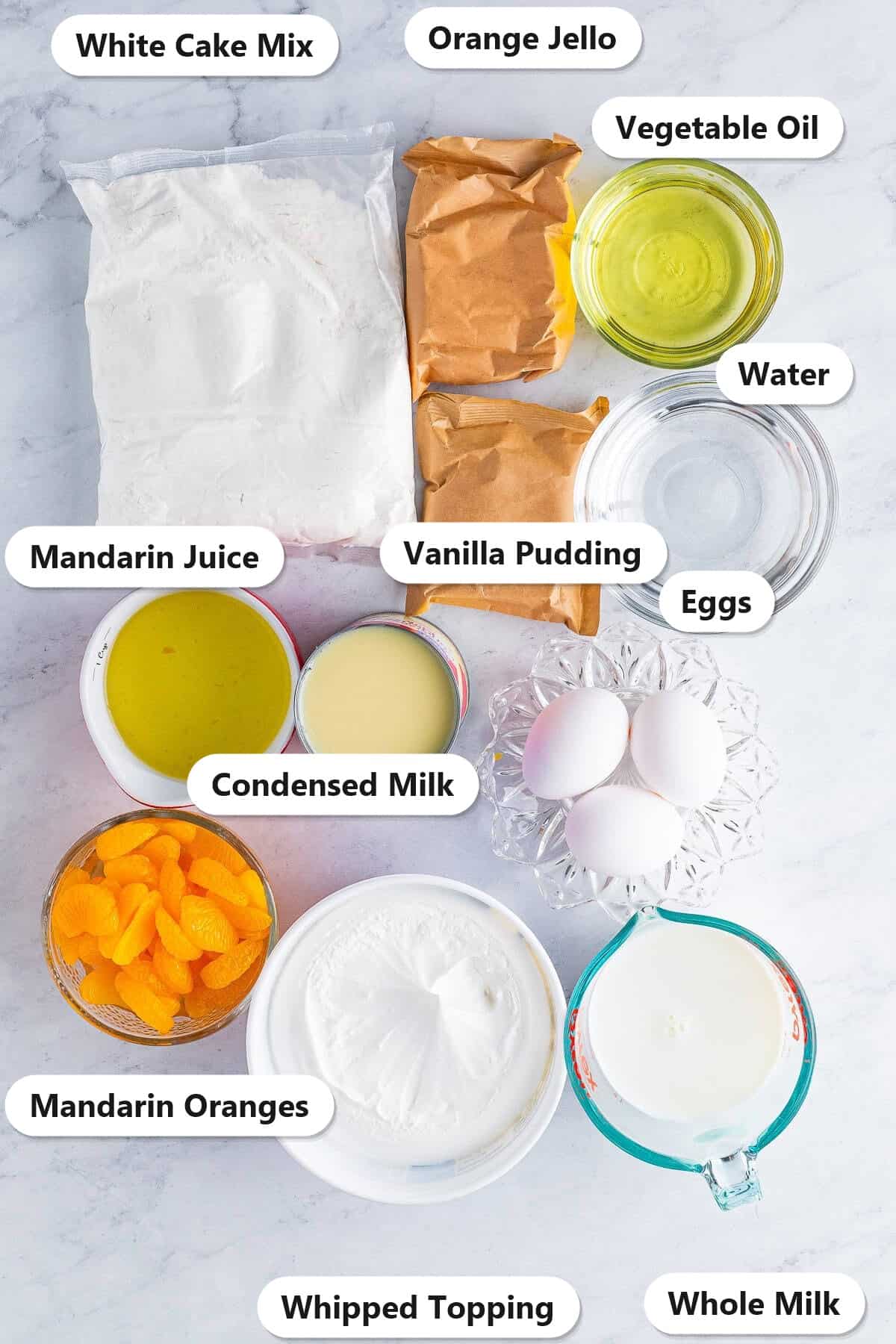 Labeled ingredients for orange creamsicle cake including white cake mix, orange jello, vanilla pudding, condensed milk, mandarin oranges, and whipped topping.