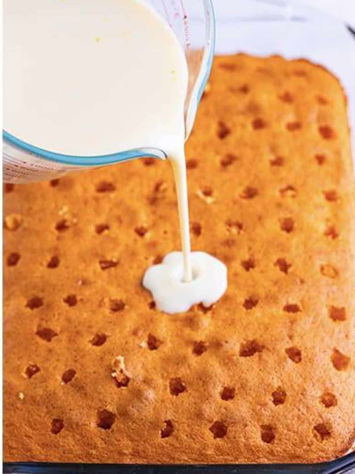 Condensed milk and mandarin juice soak poured over the poked cake.