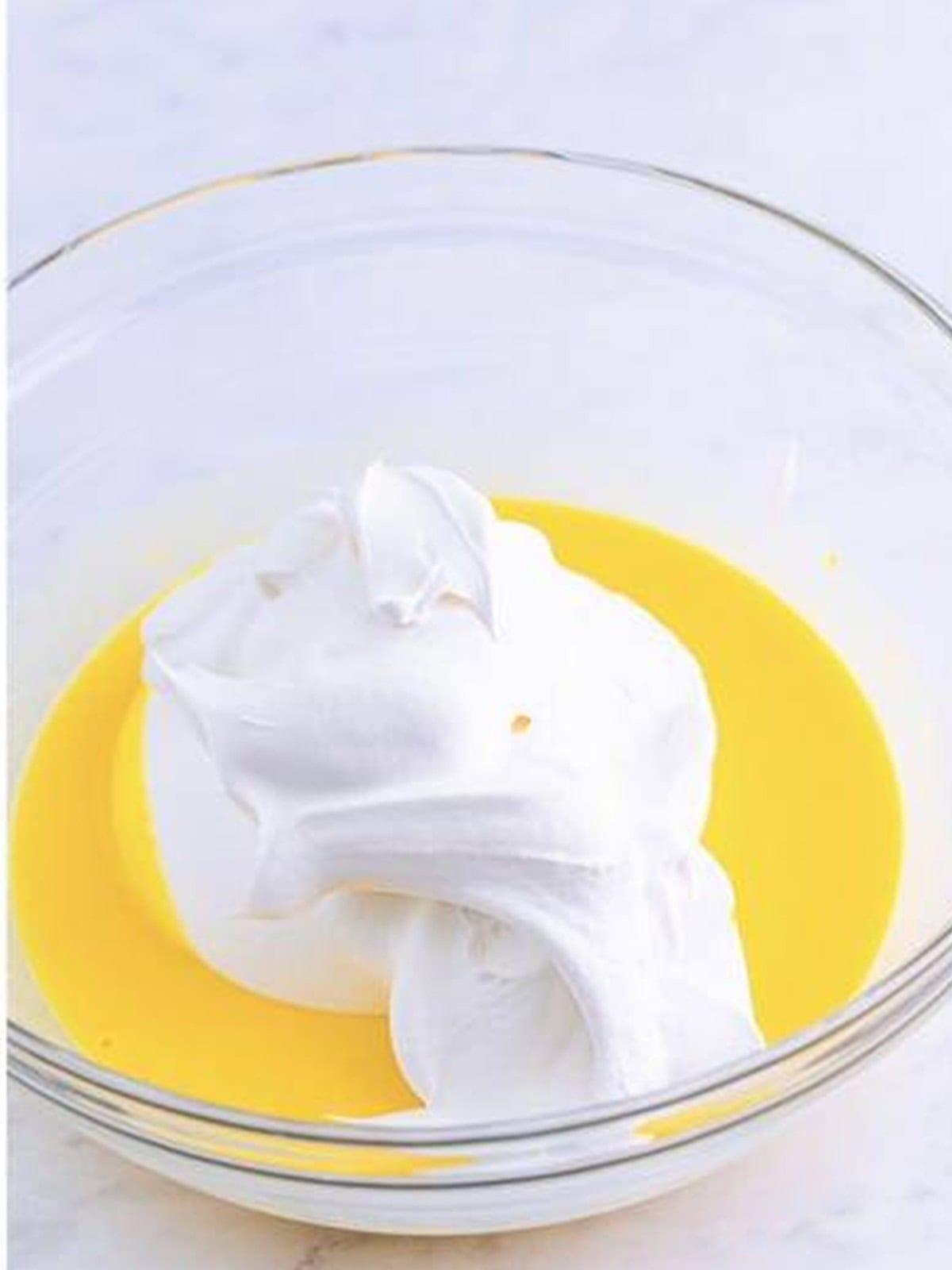 Whipped topping folded into the vanilla pudding mixture in a glass bowl.