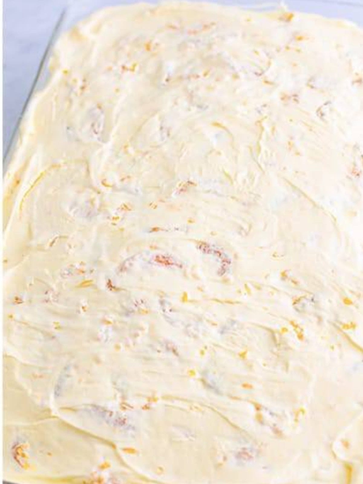 Creamy mandarin topping spread evenly over the soaked orange cake.