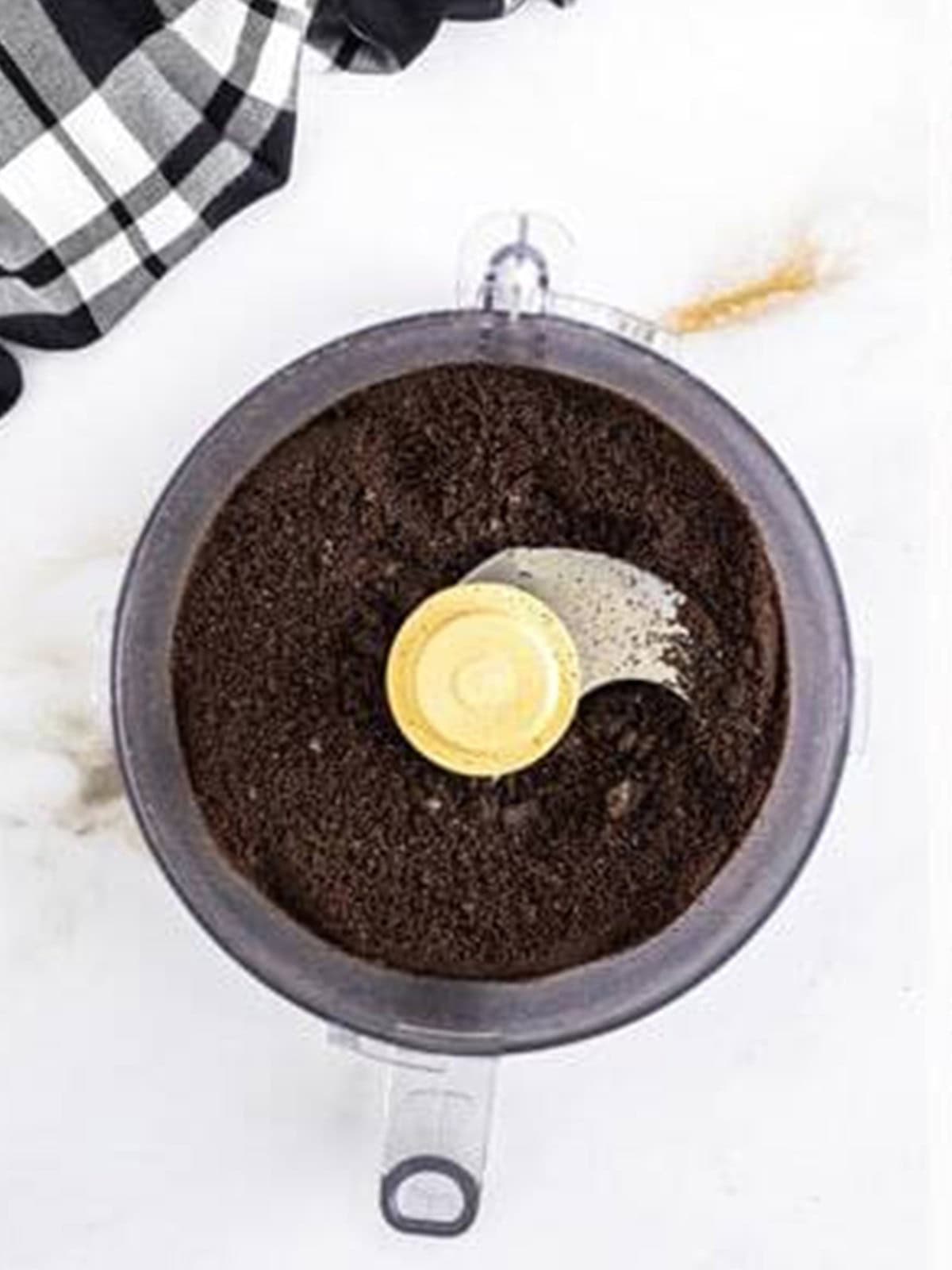 Oreos crushed into fine crumbs in a food processor for Oreo buttercream frosting.