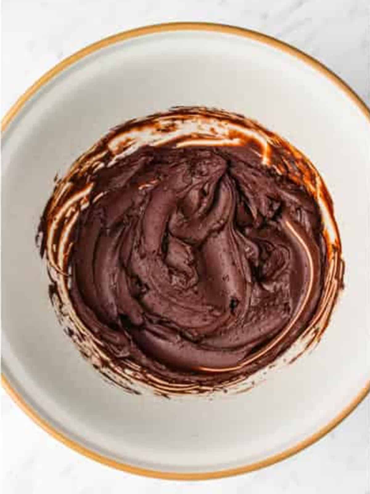 Cocoa powder mixed with boiling water into a smooth paste in a bowl for Oreo cupcakes.