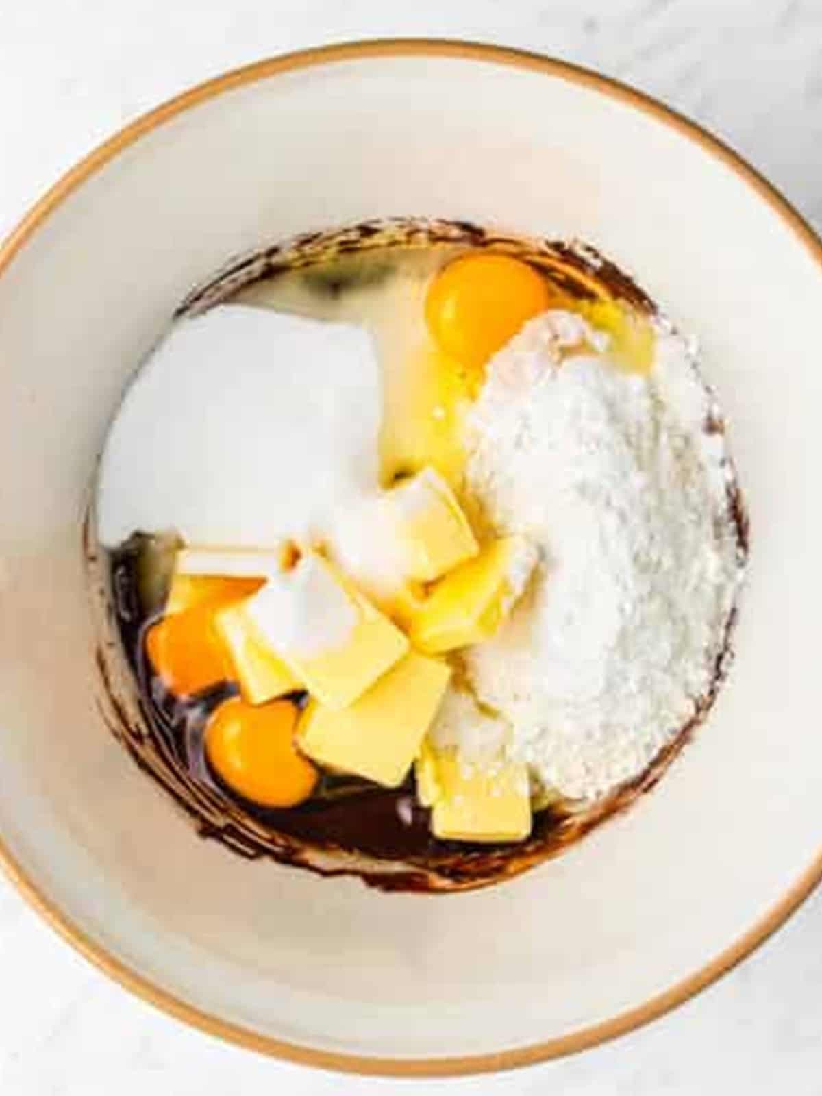 Eggs, butter, sugar, and flour added to the cocoa mixture for chocolate cupcake batter.