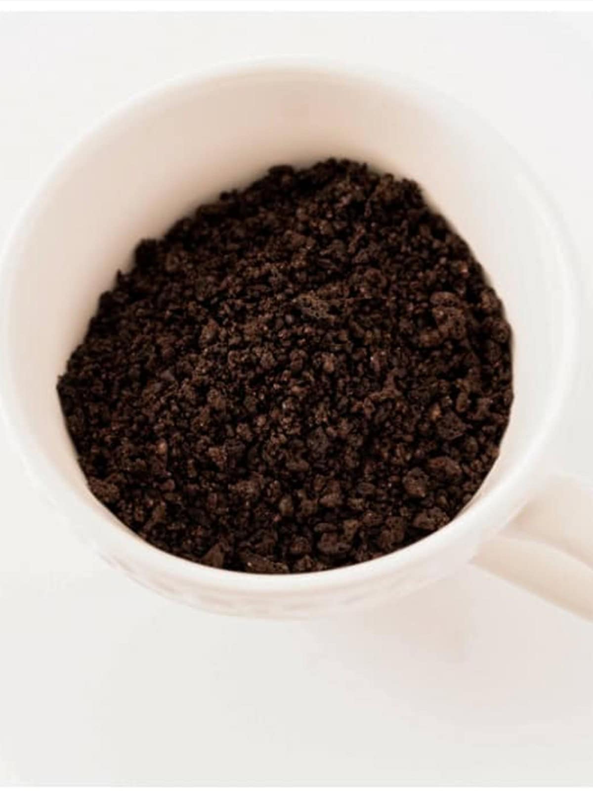 Oreo cookie crumbs added to a white microwave-safe mug.