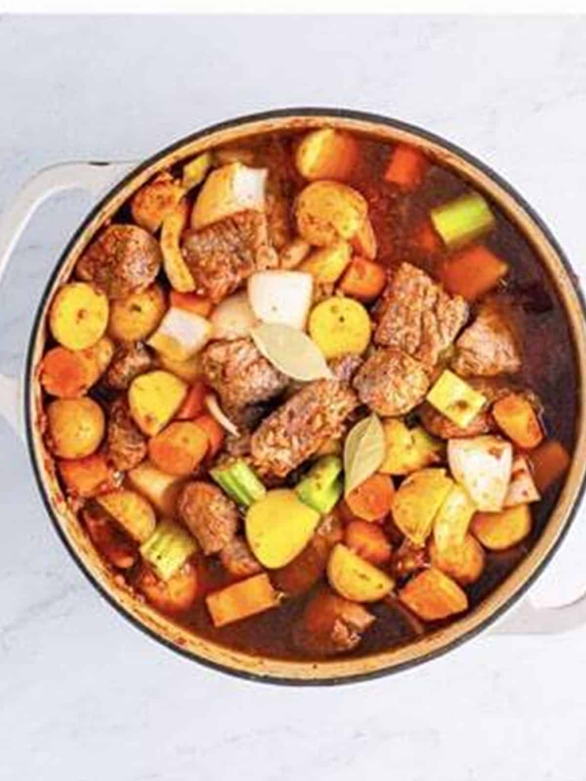 Beef stock, bay leaves, and Worcestershire sauce added before braising the stew in the oven.