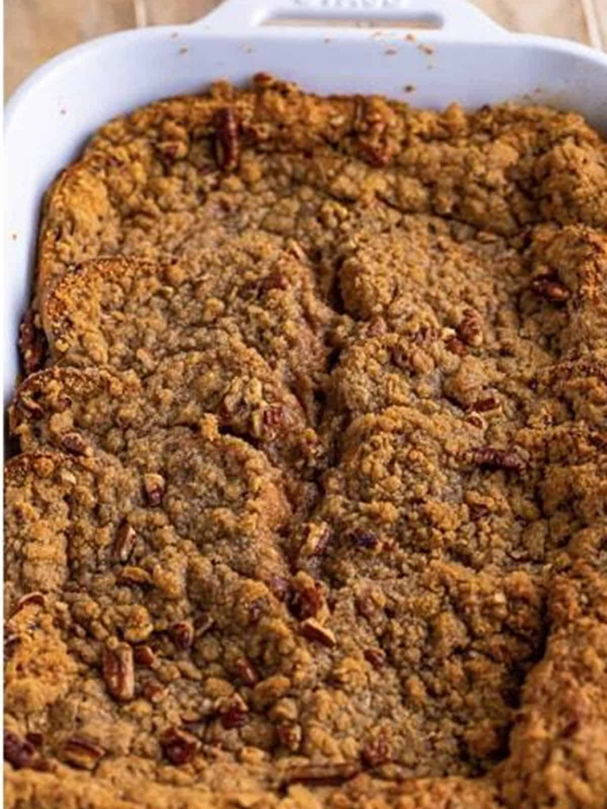 Golden baked overnight French toast casserole with pecan crumble topping in a white baking dish.