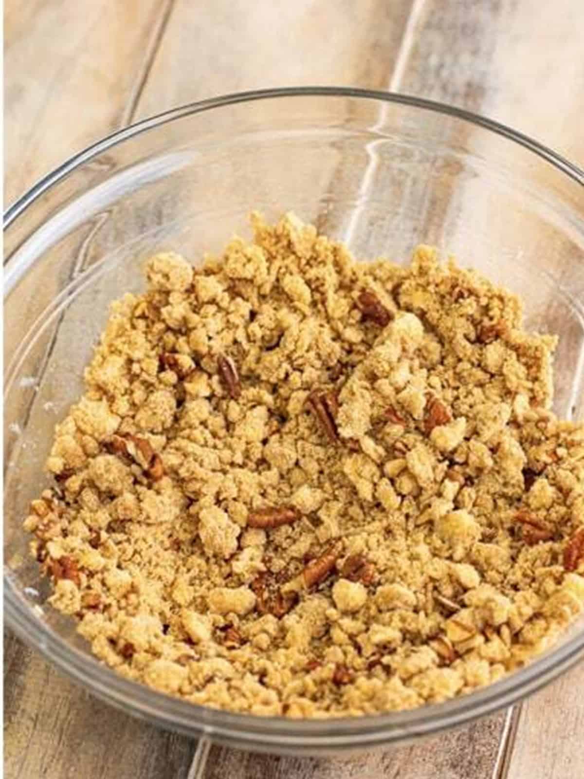 Crumble topping with brown sugar, cinnamon, flour, butter, and pecans mixed in a glass bowl.