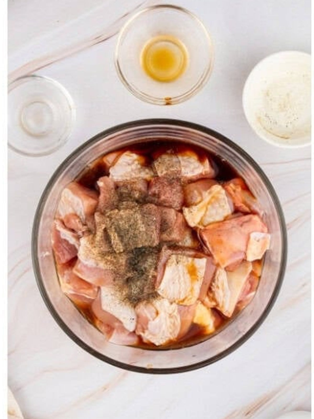 Boneless chicken thighs marinating in soy sauce and Shaoxing wine in a bowl.