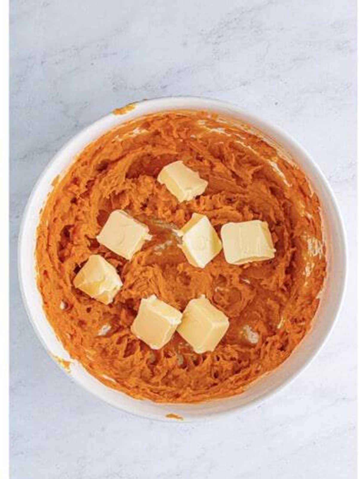 Adding cubes of butter to the whipped sweet potatoes.