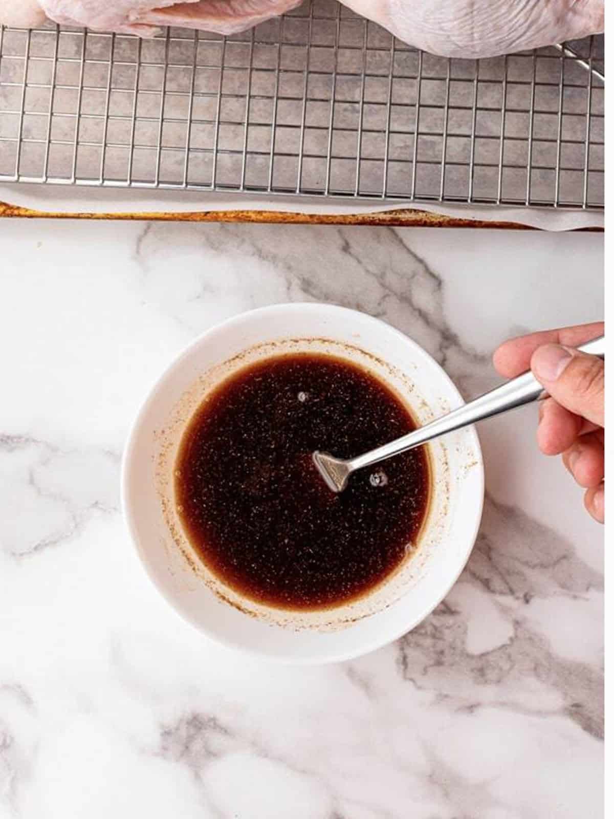 Whisking the Peking duck marinade of Shaoxing wine, honey, soy sauce, and five spice in a bowl.