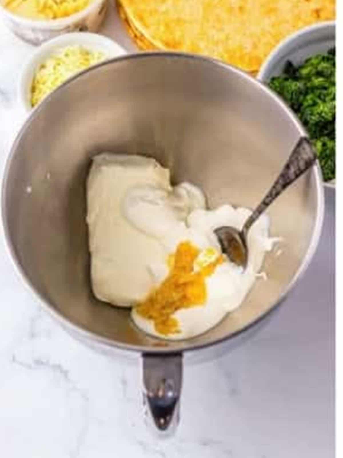 Cream cheese, sour cream, and garlic in a mixing bowl for Longhorn spinach dip.