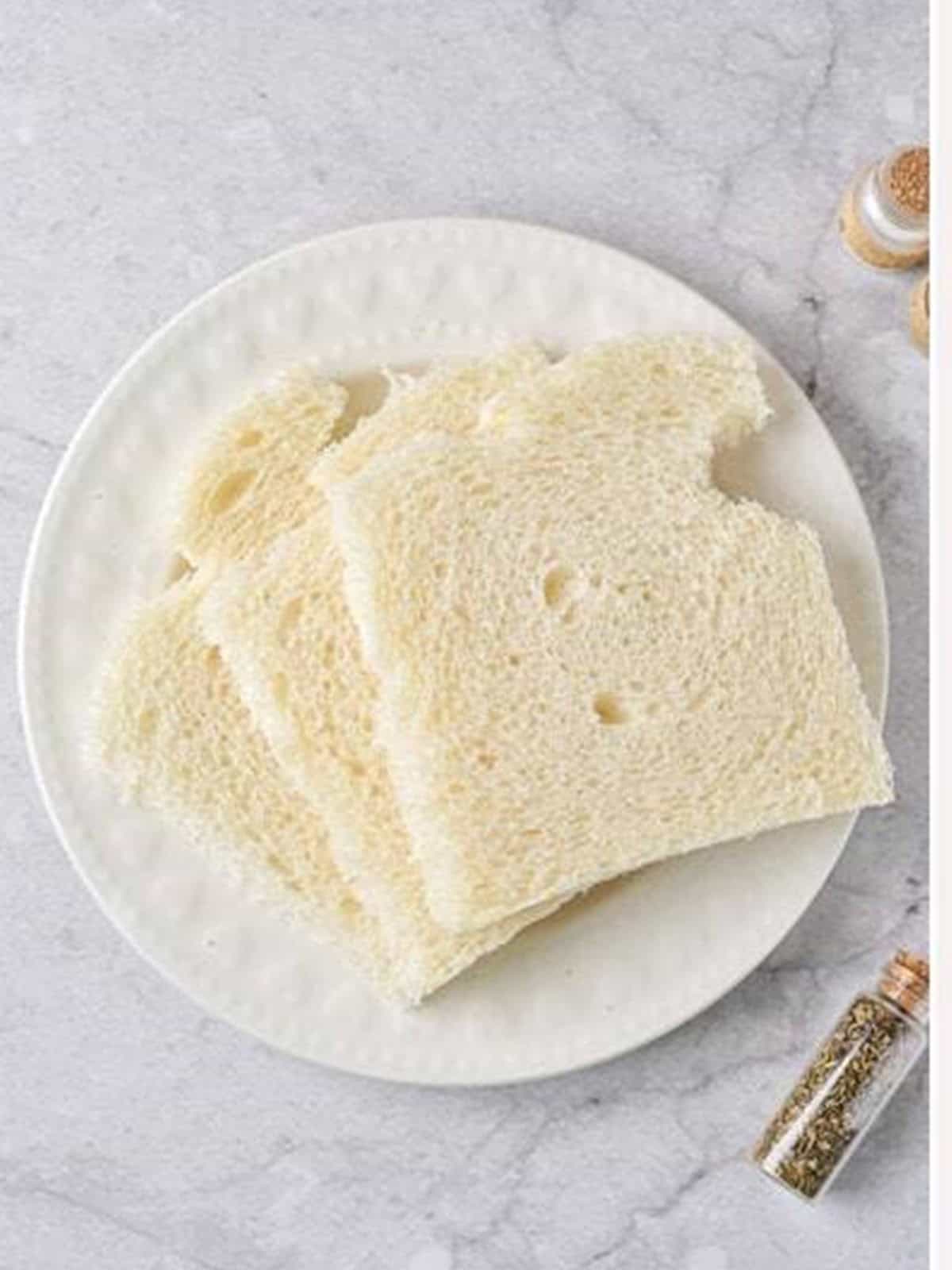 White bread slices with crusts removed on a plate for homemade panko bread crumbs.