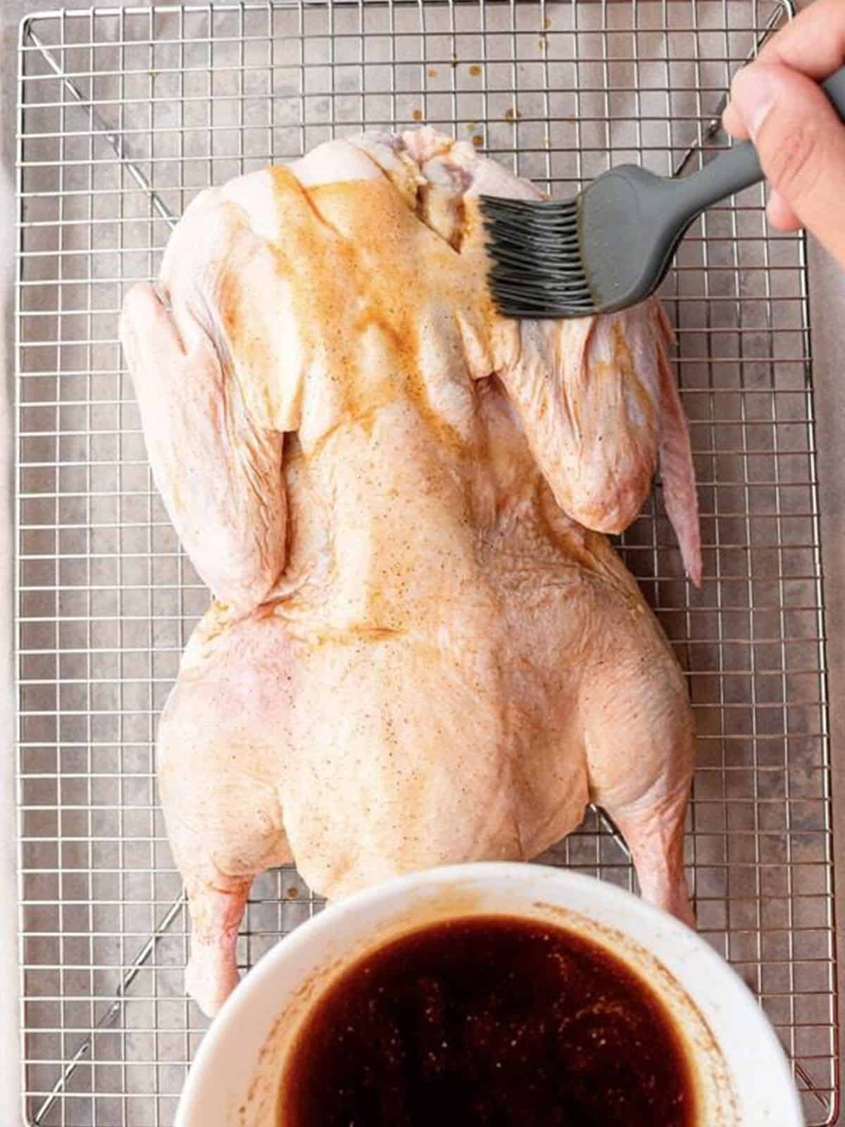 Brushing a whole raw duck with marinade before roasting for Peking duck.