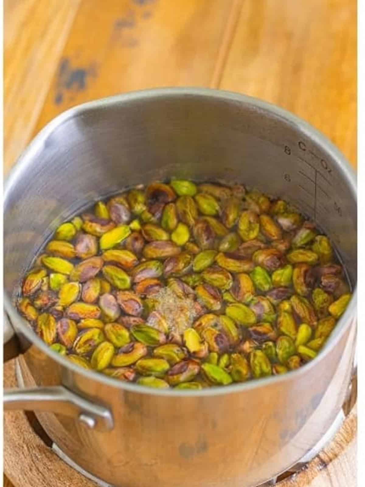 Pistachios boiling in a saucepan of water to loosen the skins.