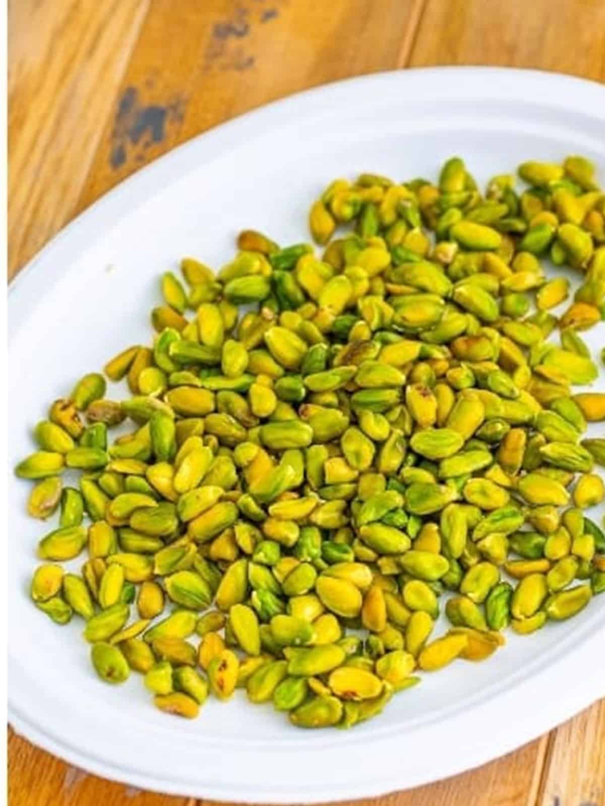 Skinned bright green pistachios on a plate after removing the skins.