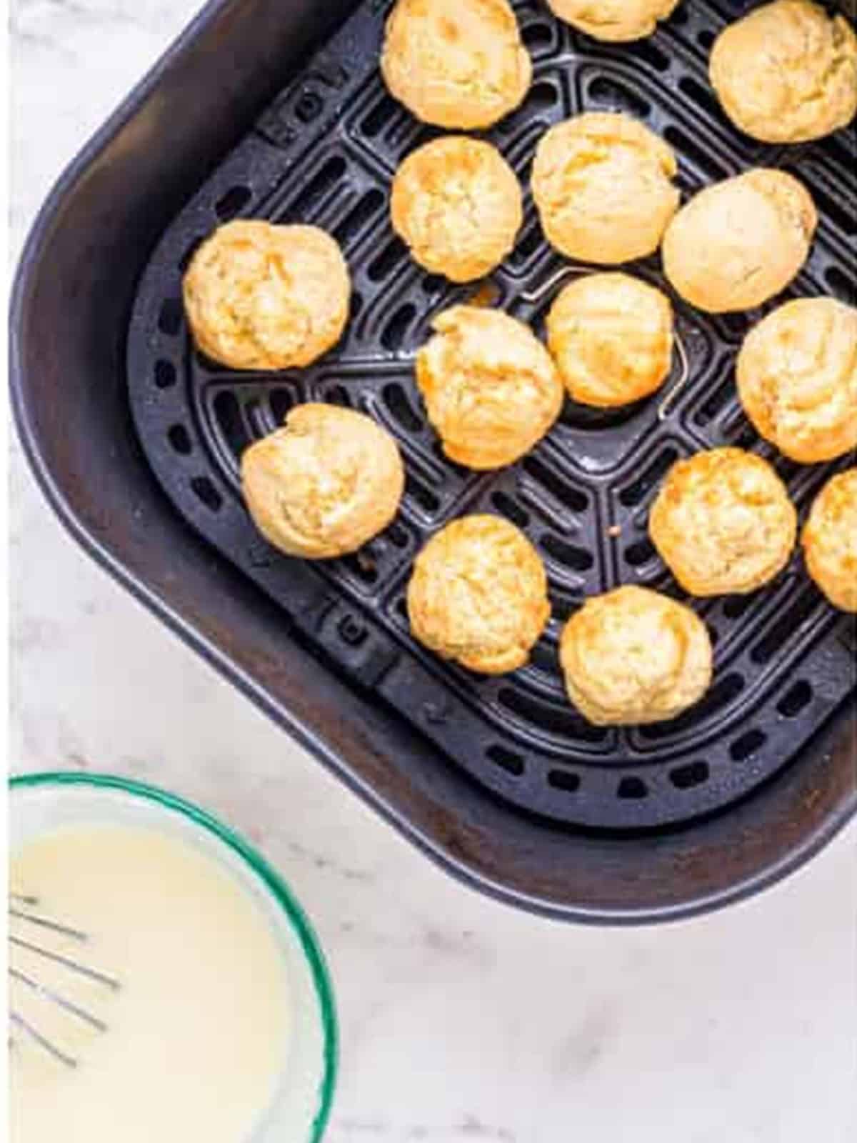 Munchkin dough balls arranged in an air fryer basket.