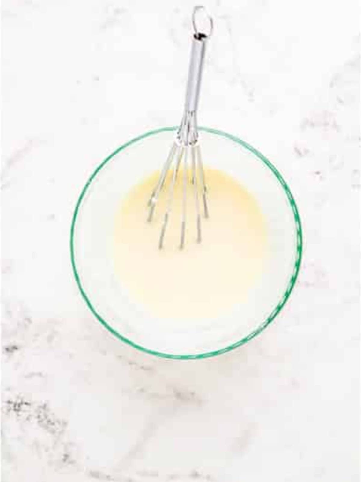Whisking powdered sugar and heavy cream into a vanilla glaze.