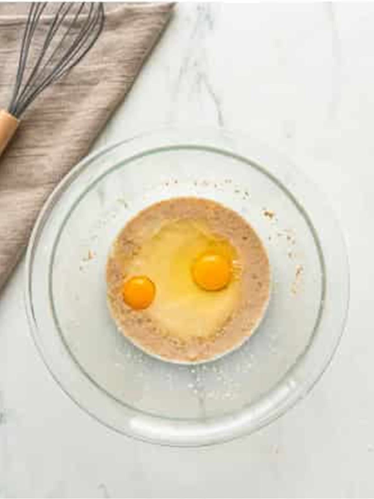 Warm milk, sugar, yeast, and eggs whisked together in a glass bowl for panettone dough.