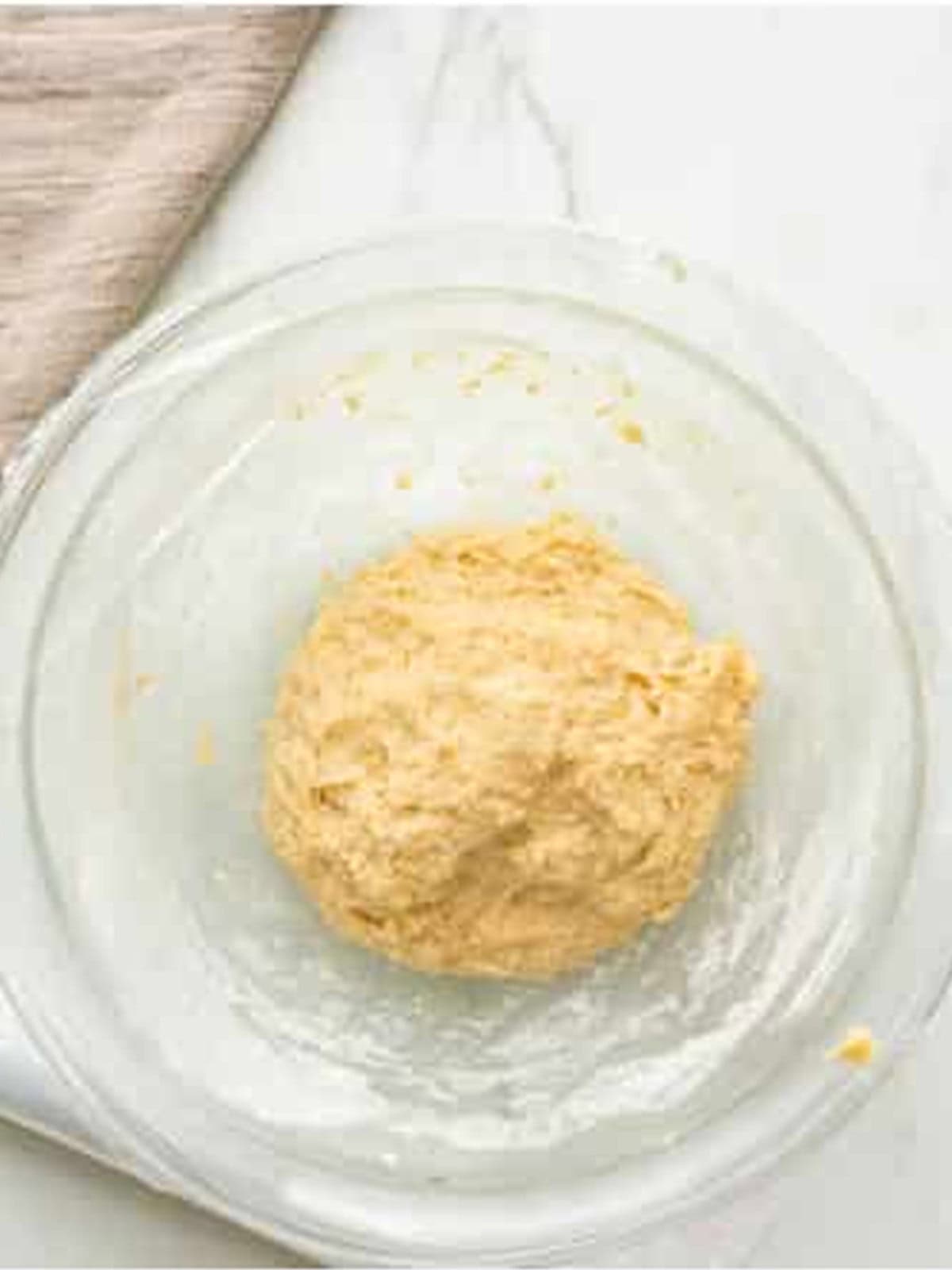 Panettone dough formed into a soft ball in a glass bowl.