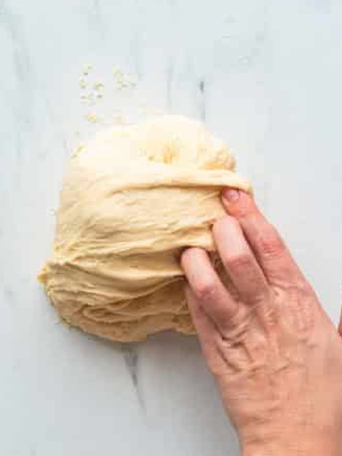 Softened butter being kneaded and folded into panettone dough.