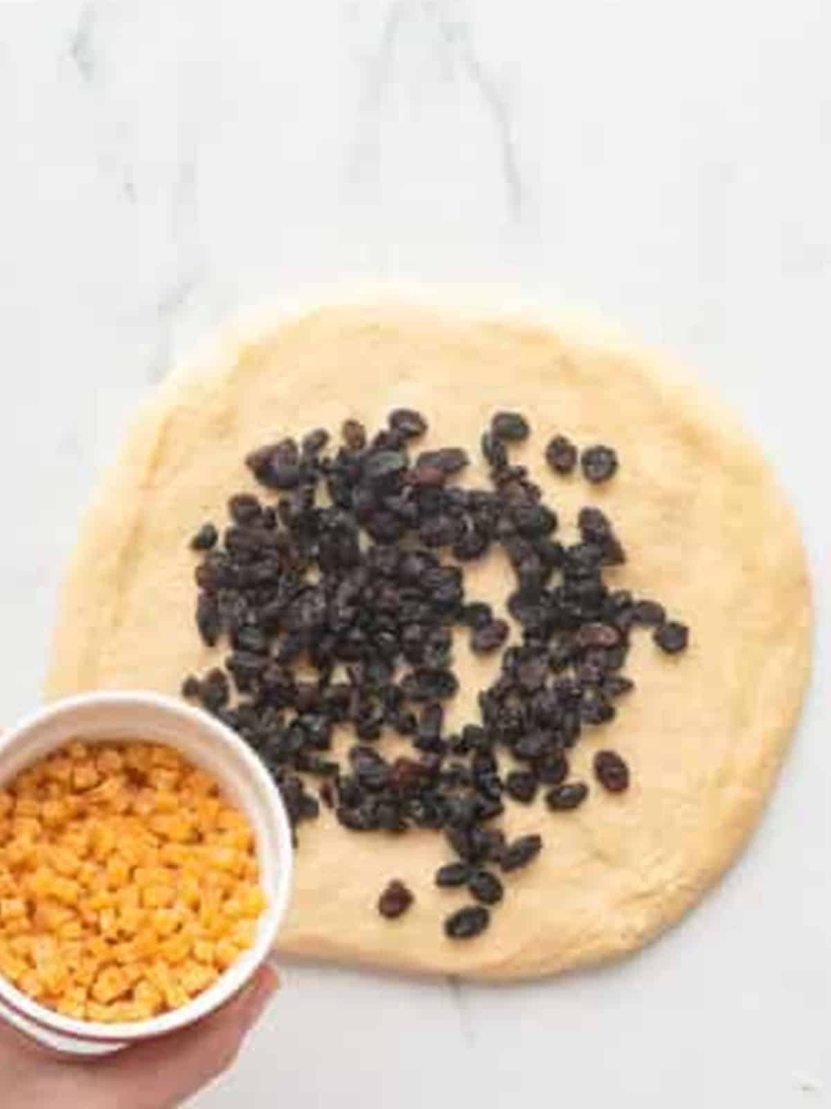 Raisins and candied orange added on top of flattened panettone dough.