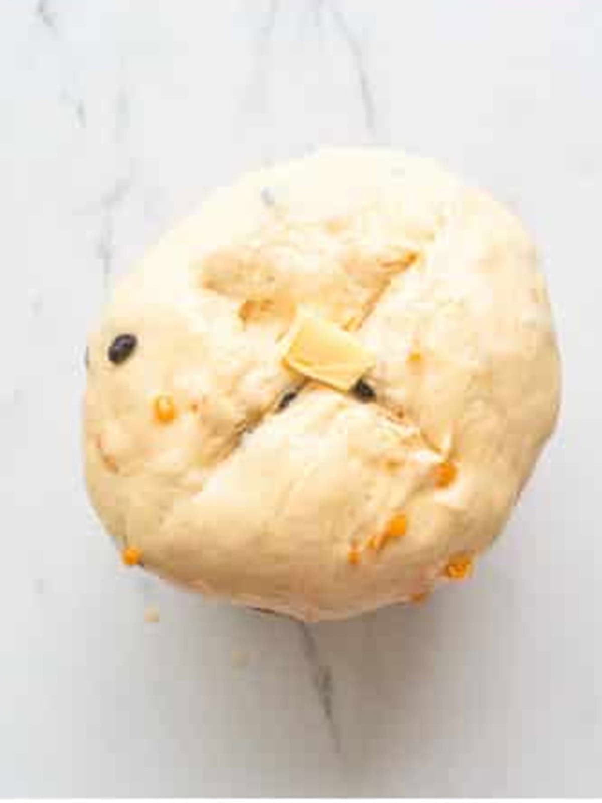 Golden baked panettone with a scored cross on top and butter melted in the center.