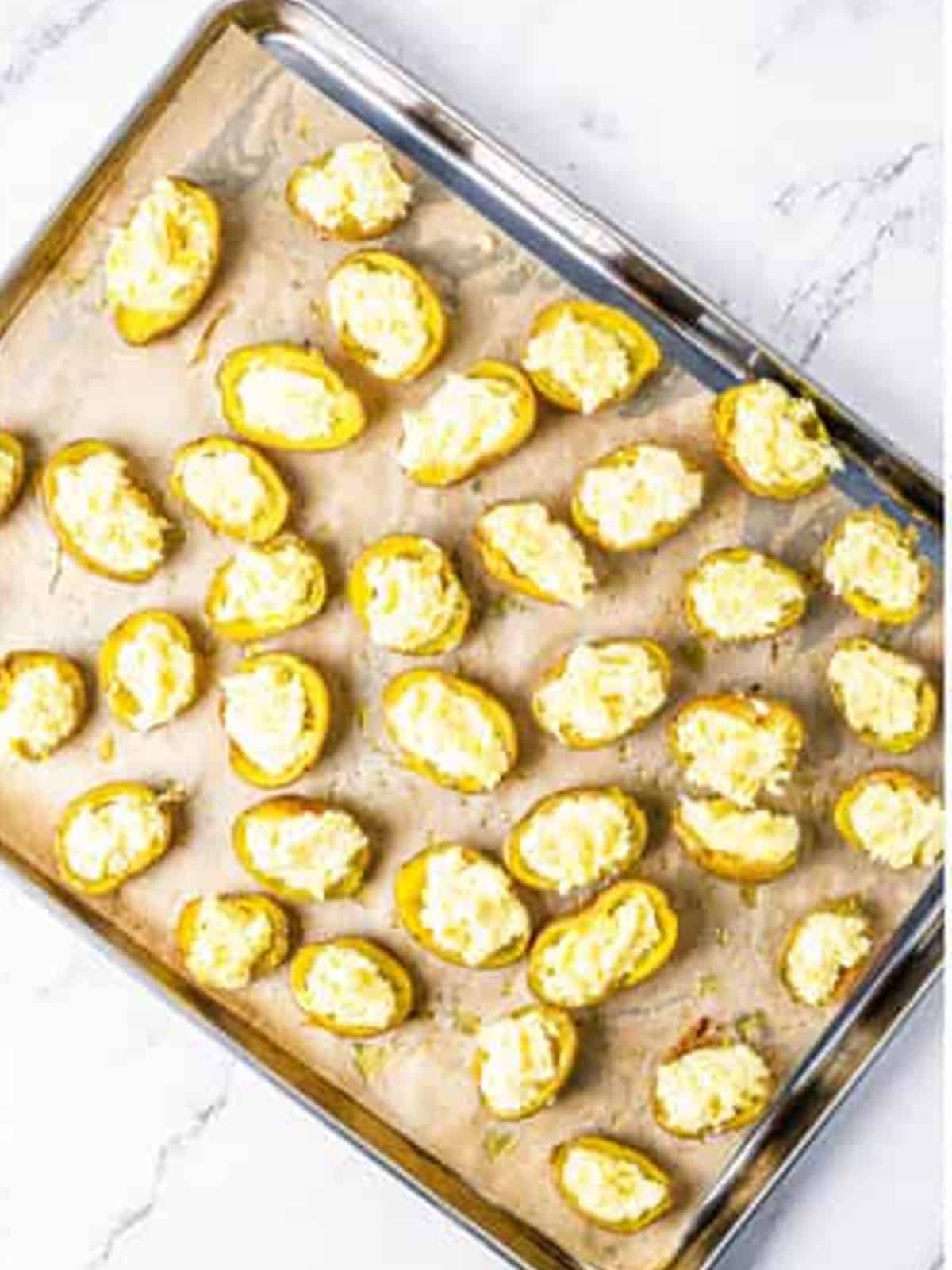 Potato skins filled with the parmesan mash on a baking sheet.