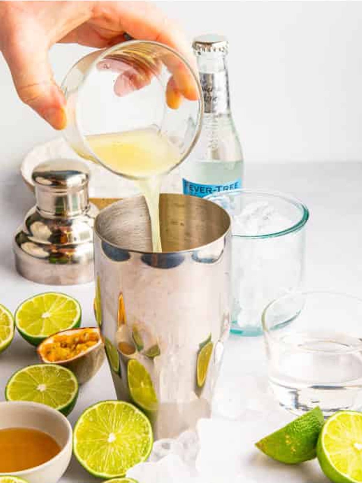 Adding fresh lime juice to the cocktail shaker.