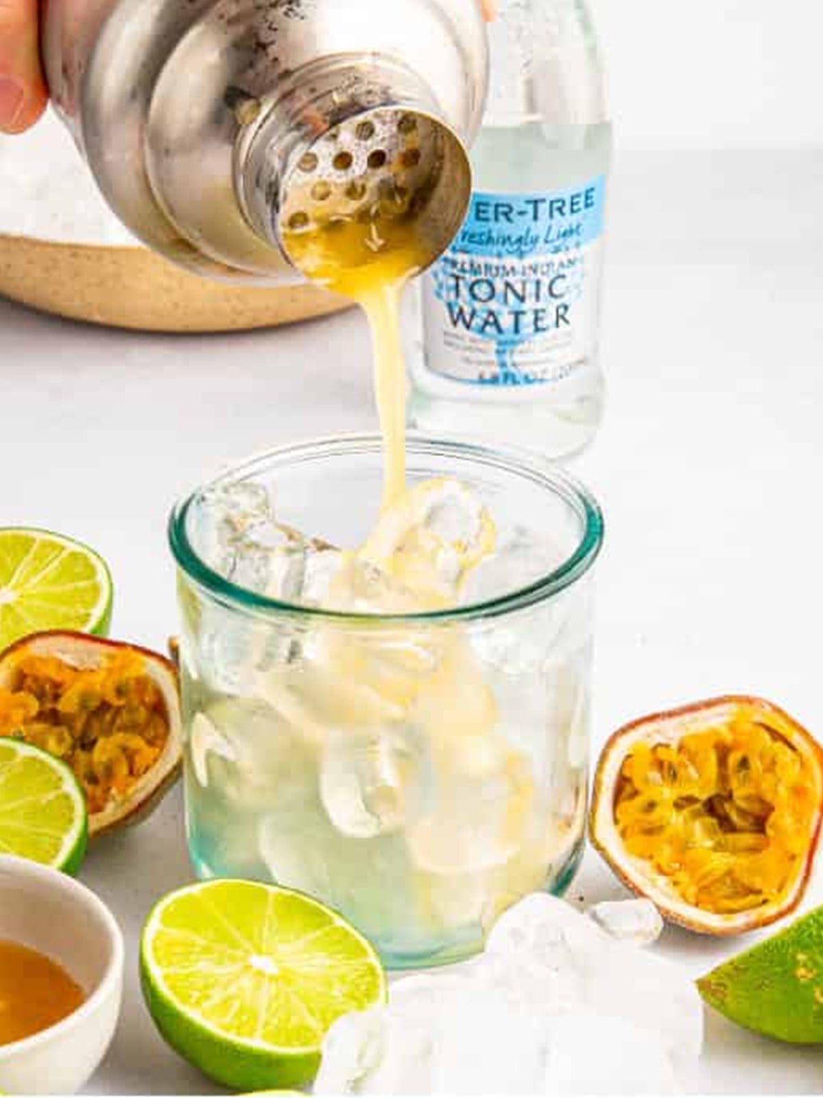 Straining the passion fruit cocktail into a glass of crushed ice.