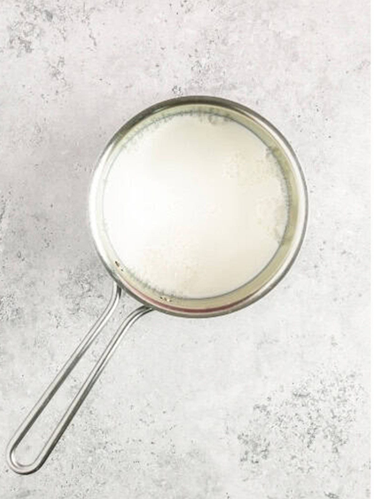 Whisking milk and sugar in a saucepan to start pastry cream.