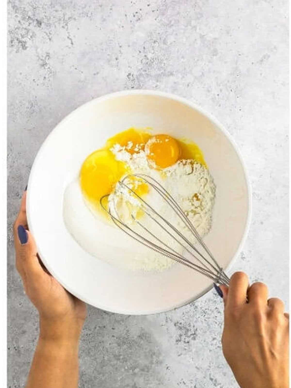 Whisking egg yolks, whole egg, cornstarch, and sugar in a bowl.