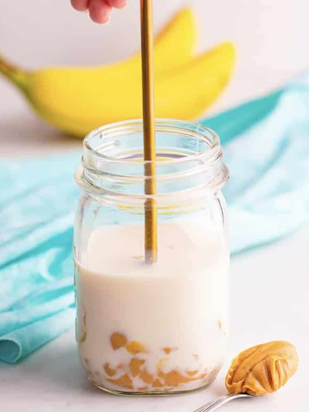 Milk, peanut butter, and maple syrup stirred together in a mason jar.