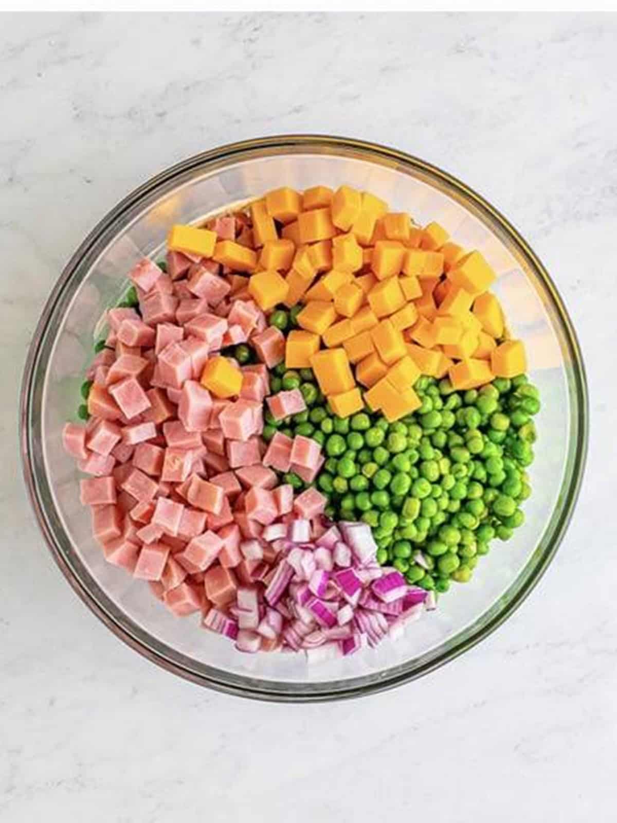Sweet peas, diced ham, cheddar cheese cubes, and red onion added on top of the creamy dressing.