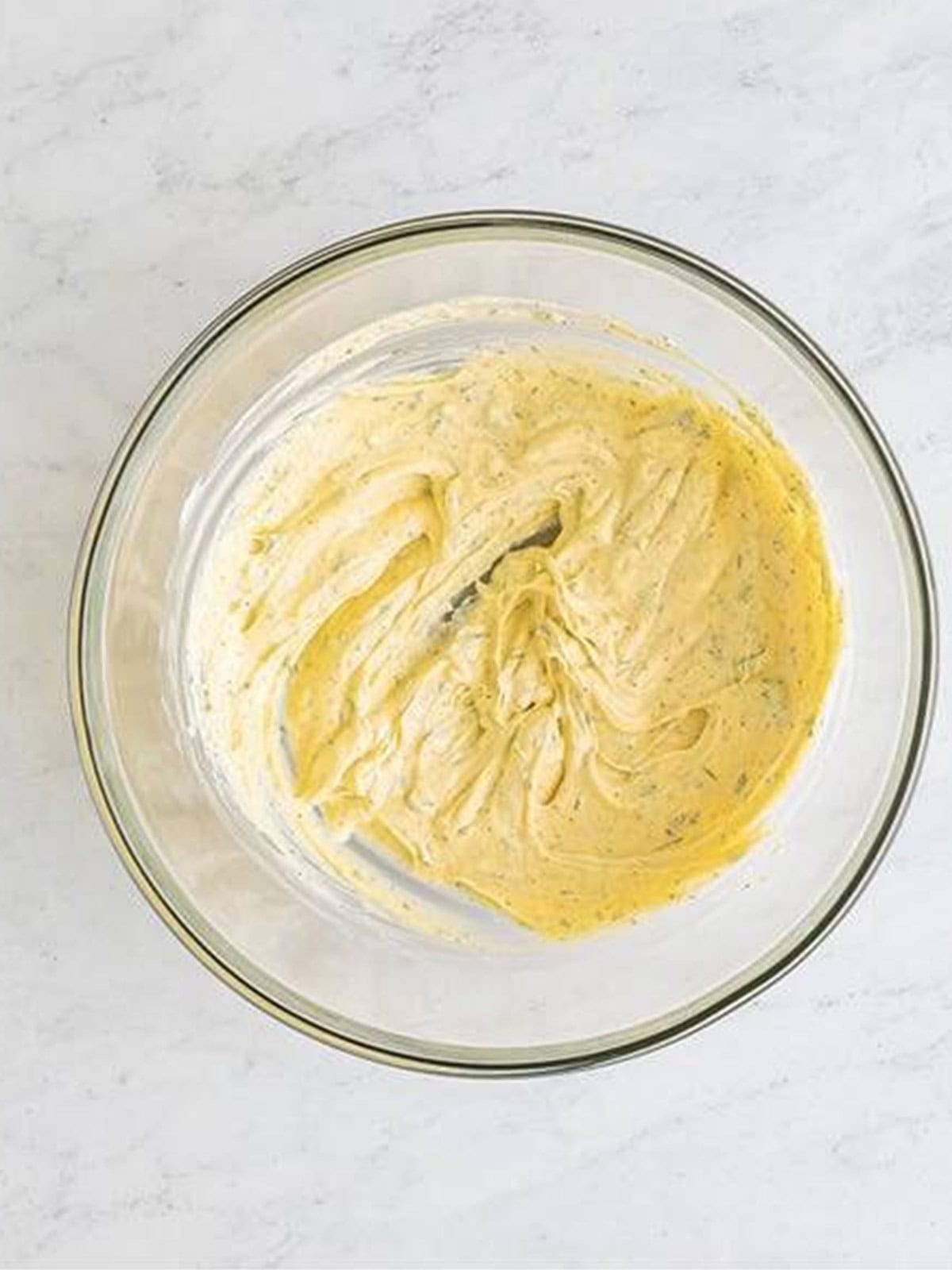Creamy pea salad dressing whisked smooth in a glass mixing bowl.