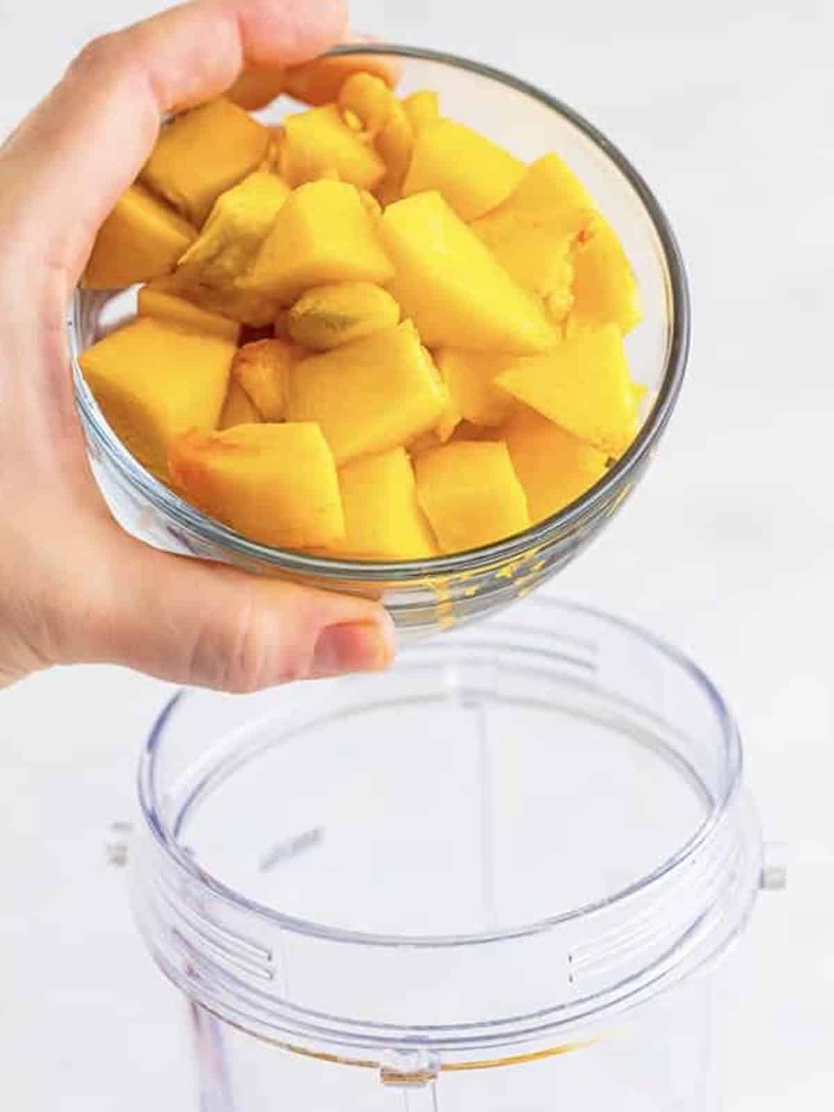 Chopped peaches added to a blender with simple syrup and raspberries for peach bellini puree.