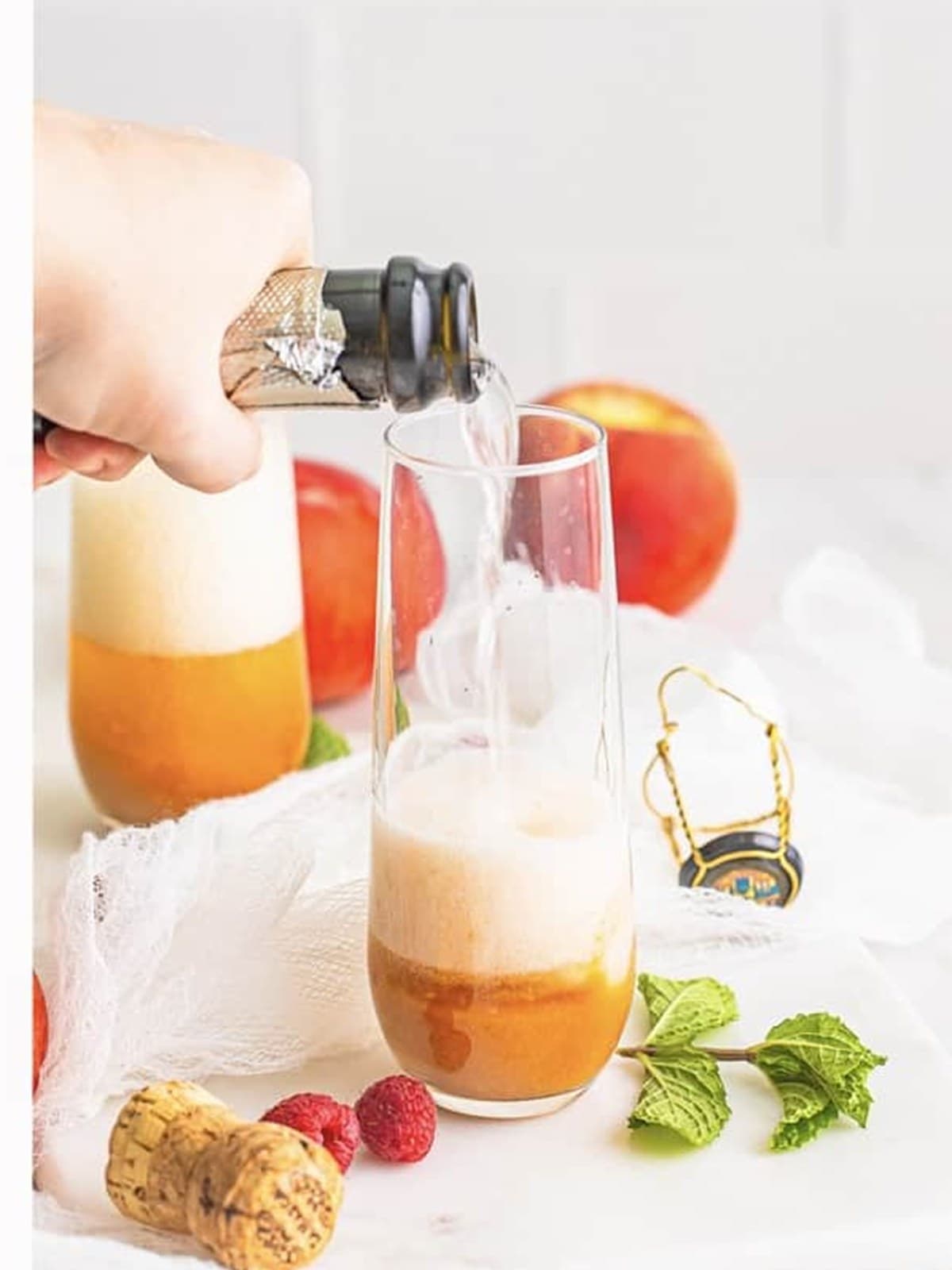 Prosecco poured into a glass with peach puree to make a peach bellini.