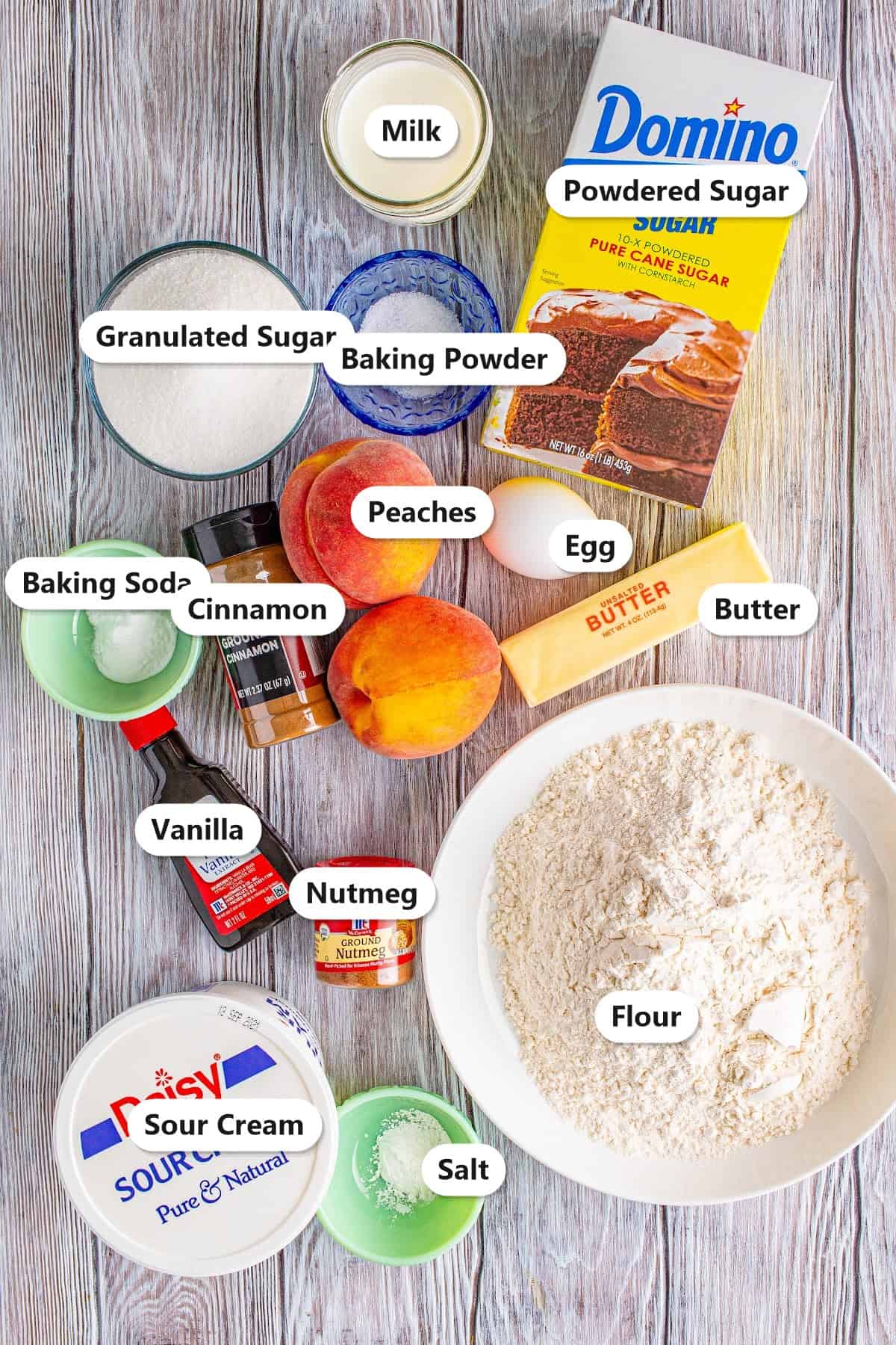 Southern Fresh Peach Bread ingredients including flour, granulated sugar, powdered sugar, baking soda, baking powder, cinnamon, nutmeg, salt, egg, butter, sour cream, vanilla, milk, and fresh peaches labeled on a board.