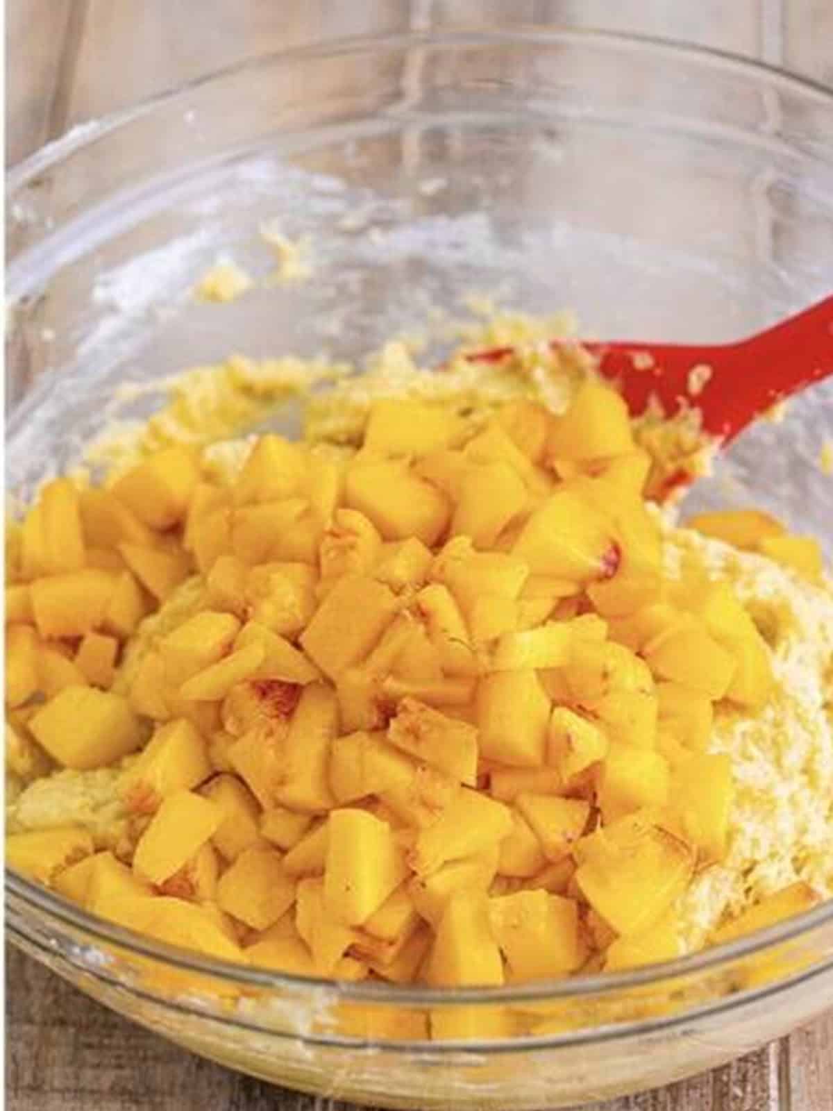 Folding diced fresh peaches into the fritter batter.