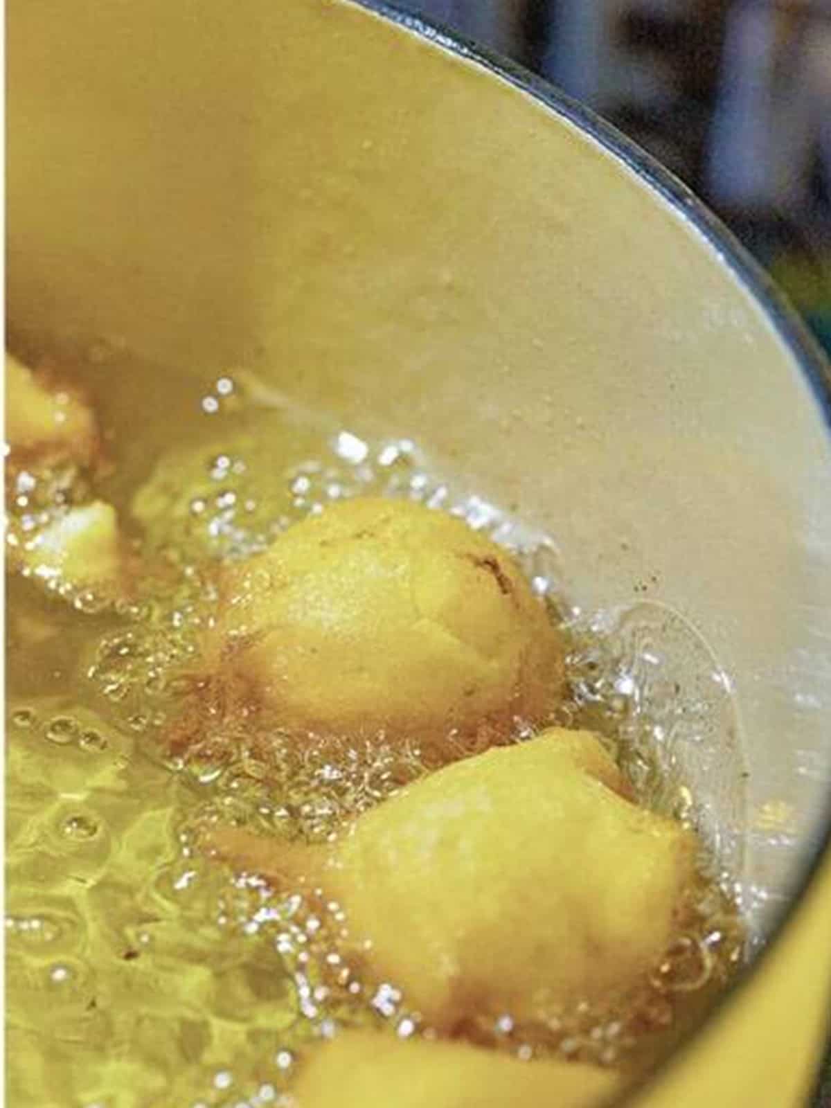 Frying Peach Fritters in hot oil until golden.