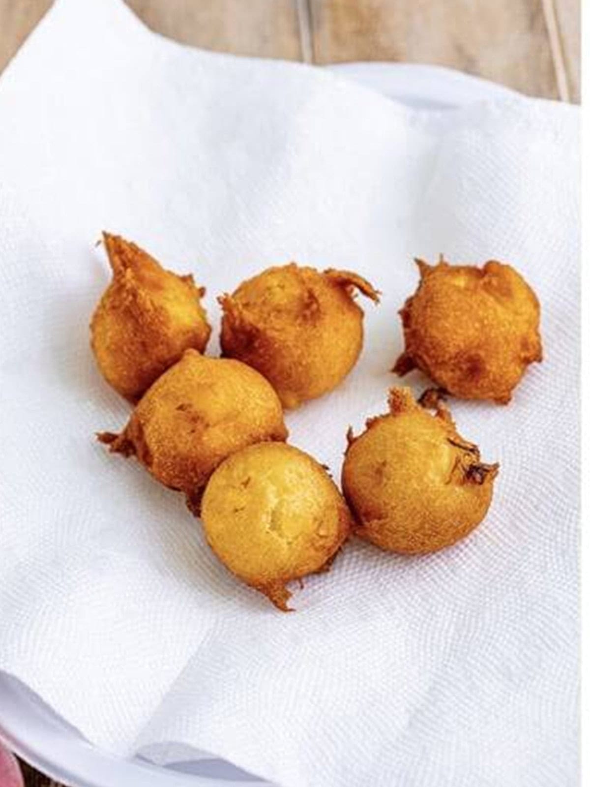 Draining fried Peach Fritters on a paper towel.