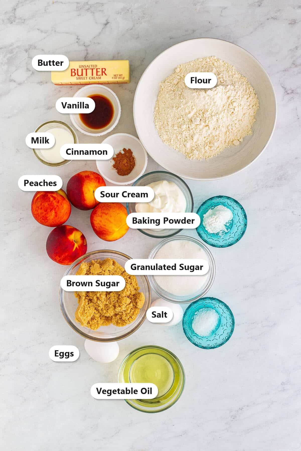 Peach muffin ingredients labeled including butter, flour, vanilla, milk, cinnamon, peaches, sour cream, baking powder, brown sugar, granulated sugar, salt, eggs, and vegetable oil.
