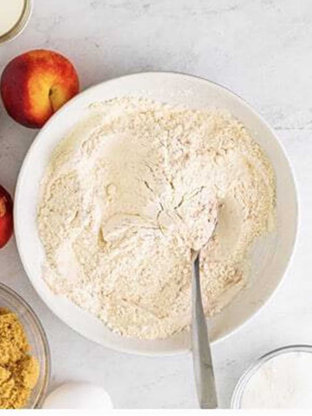 Flour, baking powder, salt, and cinnamon stirred together in a bowl.