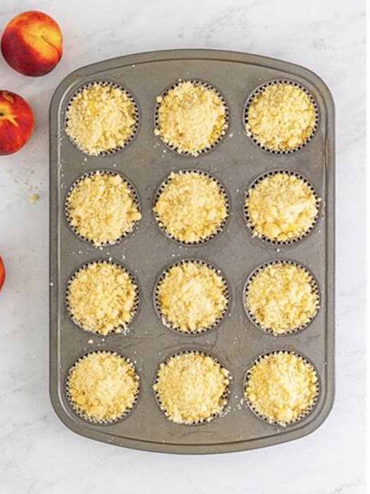Crumbly streusel topping added over the unbaked peach muffins.