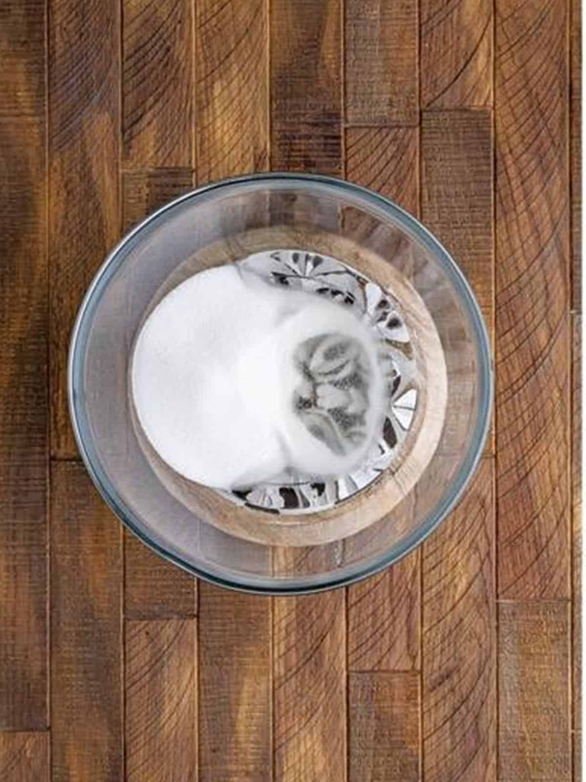 Granulated sugar and corn syrup combined in a glass bowl before microwaving.