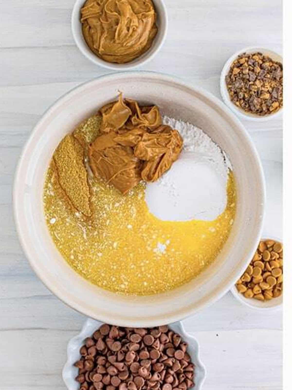 Melted butter, graham cracker crumbs, powdered sugar, and peanut butter mixed in a bowl for peanut butter bars.