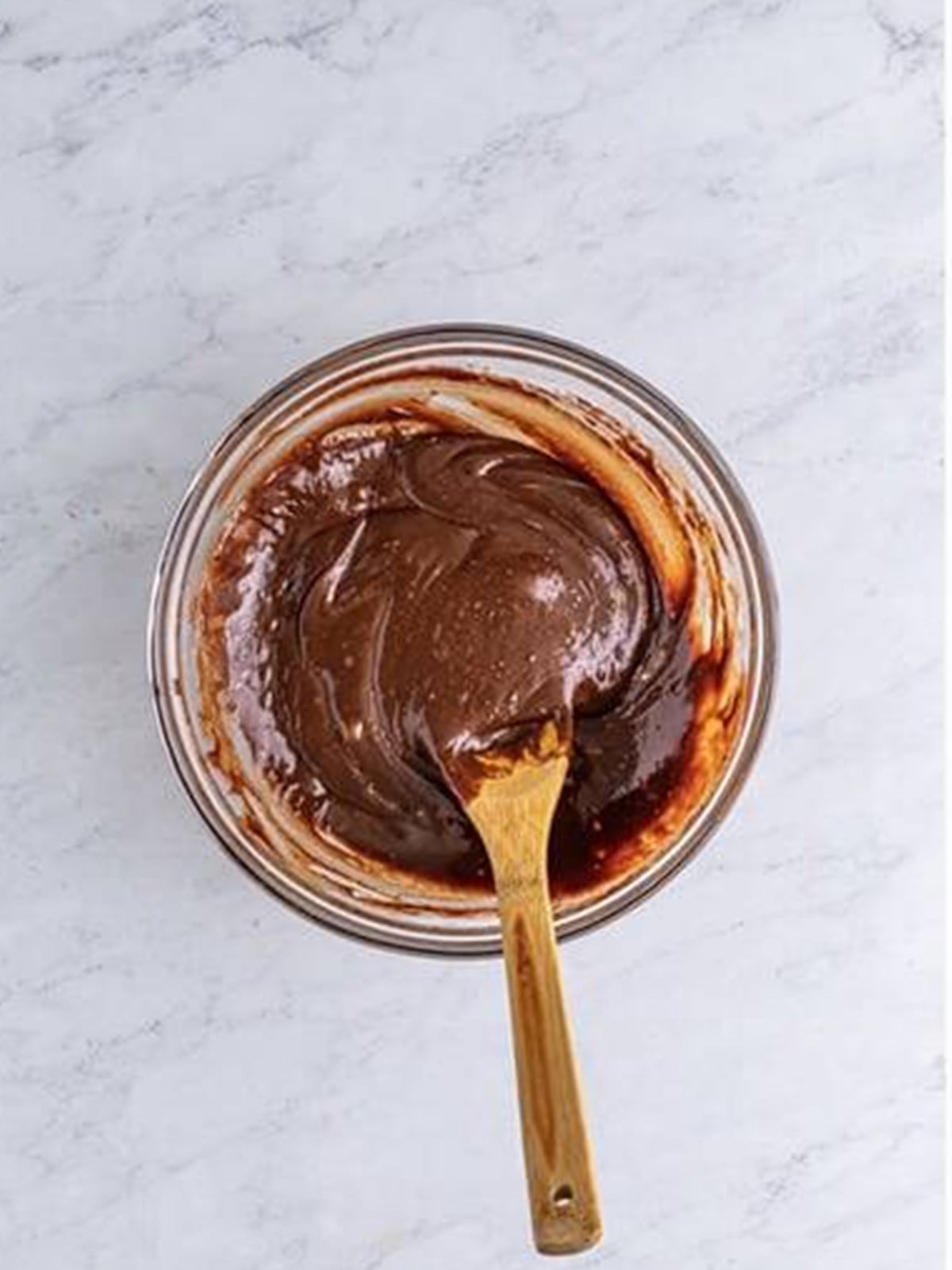 Chocolate brownie batter mixed in a glass bowl for peanut butter brownies.
