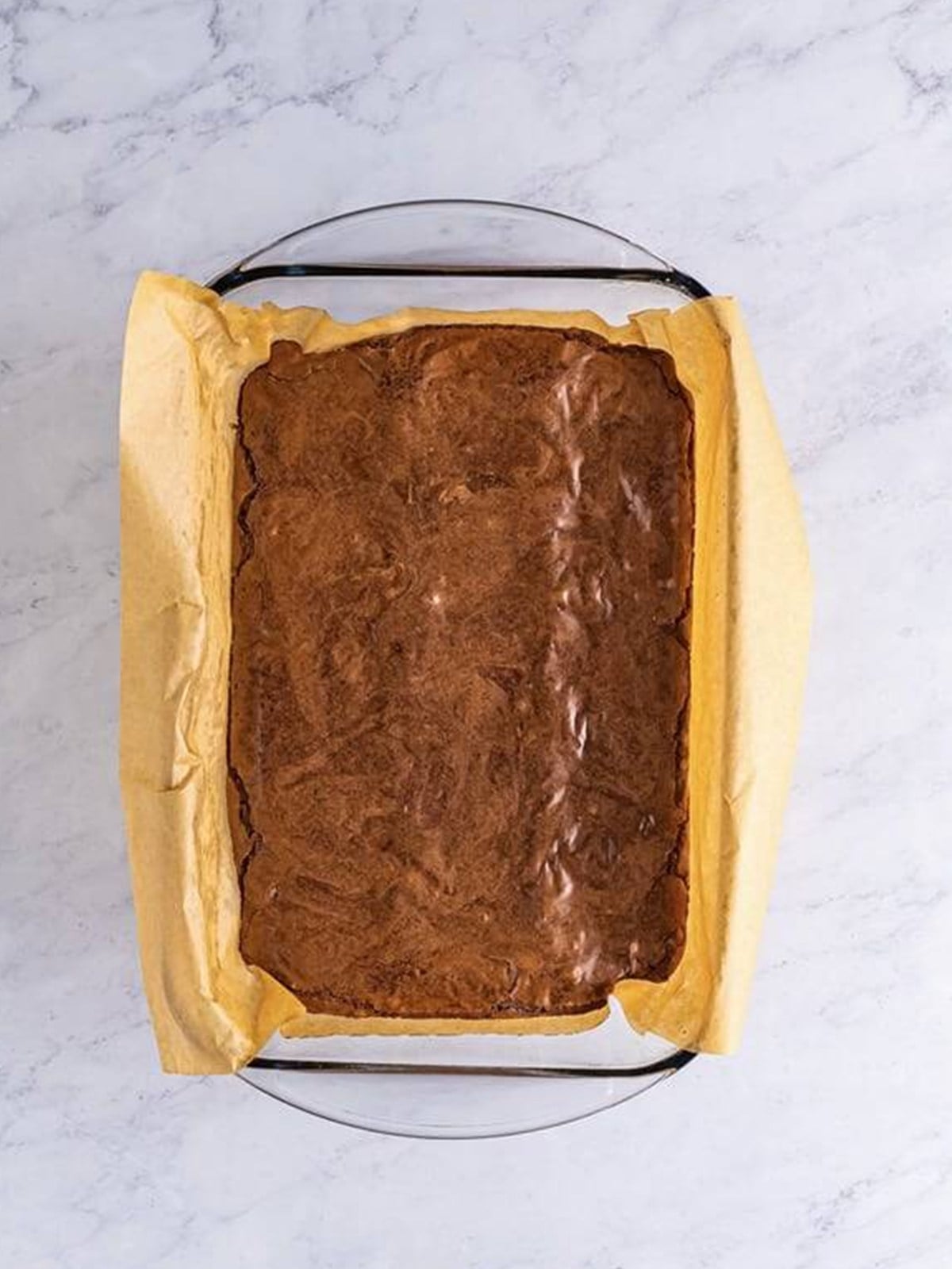 Baked peanut butter cup stuffed brownies in a parchment lined pan.