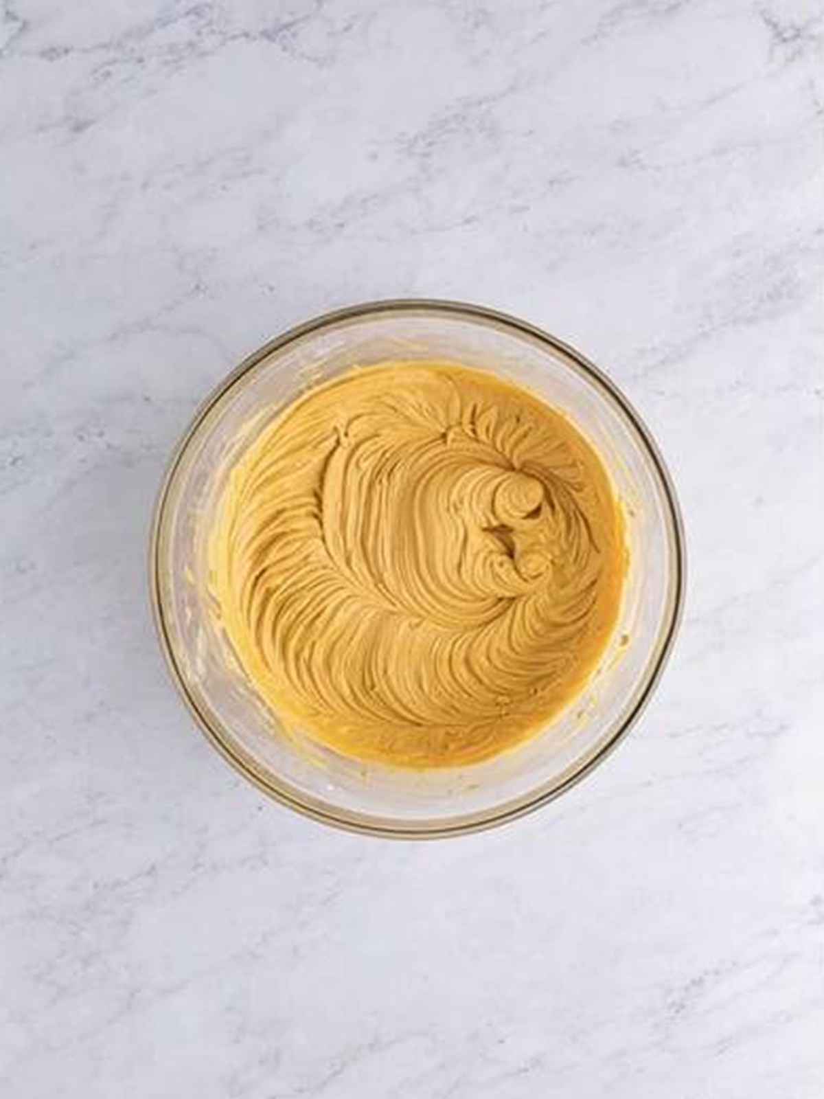 Whipped fluffy peanut butter frosting in a glass bowl.