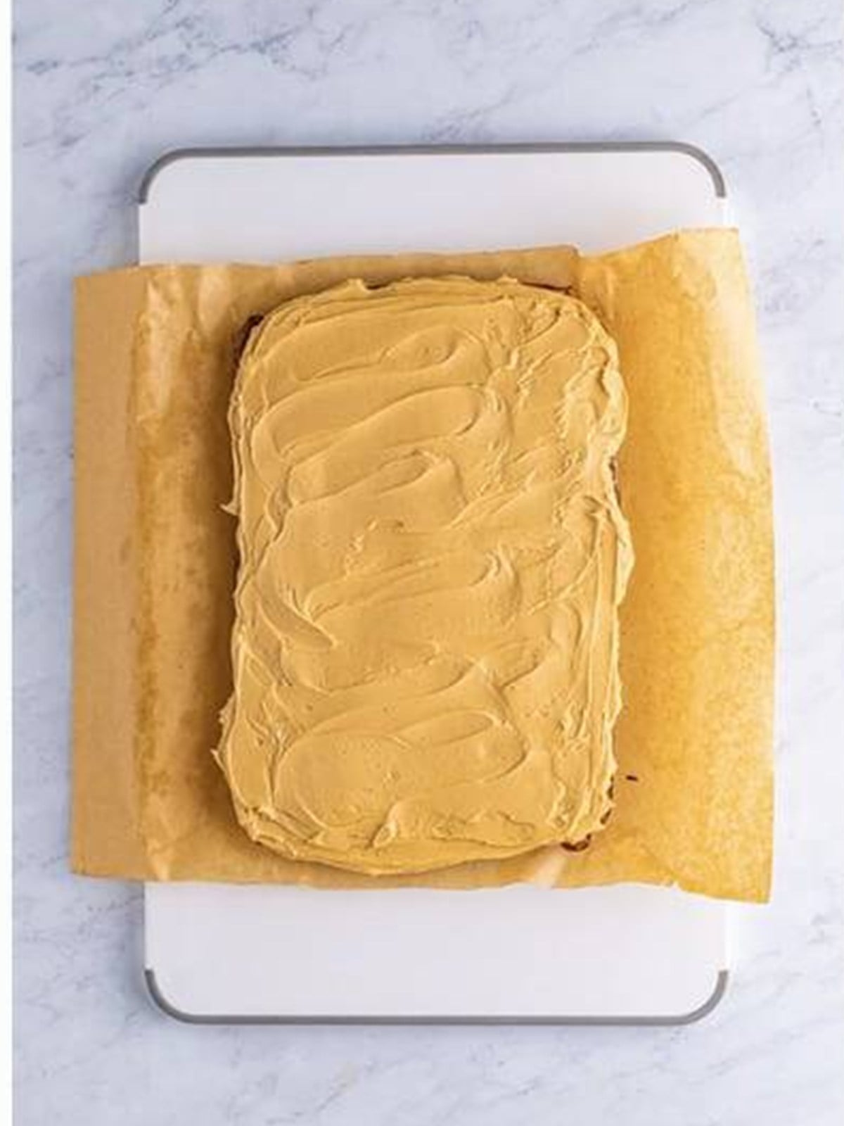 Peanut butter frosting spread over a pan of brownies.