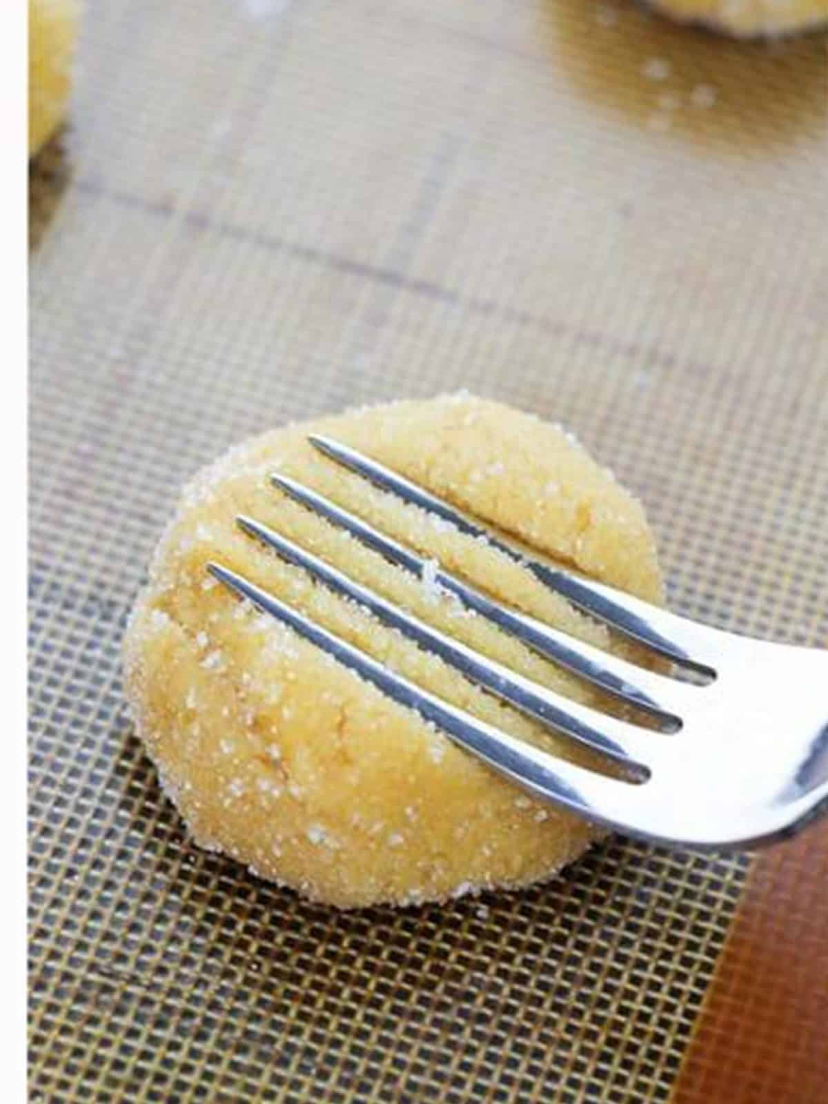 Pressing a peanut butter cookie dough ball with a fork.